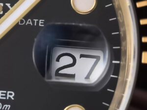 Close-up of the date display on the Submariner Date Yellow Gold with Black Dial (40mm), showing 27 under a magnified lens.