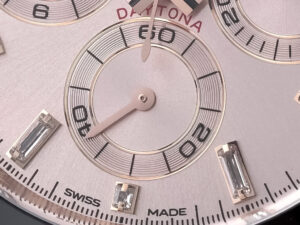 Close-up of the pink dial on a Cosmograph Daytona Rose Gold Oysterflex, showcasing sub-dials and baguette hour markers.