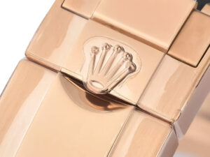 Close-up of the clasp on the Cosmograph Daytona Rose Gold Oysterflex with pink dial, showcasing its iconic crown logo.