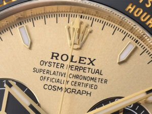 Close-up of the Cosmograph Daytona Yellow Gold Oysterflex 2023 with Champagne Dial, highlighting logo emblem and text.