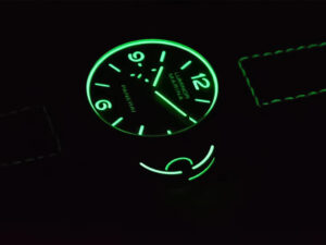 Luminor 1950 44 3 Days Automatic Carbotech watch with glowing green numerals, markers, and black sunburst dial in darkness.