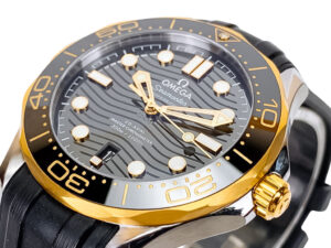 Seamaster Diver 300 watch in stainless steel, black dial with wave pattern, gold bezel, and rubber strap (42mm).