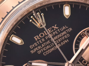 Close-up of the Cosmograph Daytona Rose Gold with Black Dial, showing intricate details and branding on the watch face.