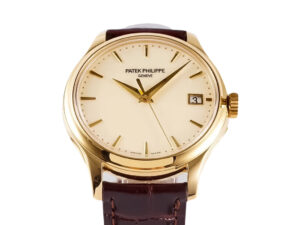 Calatrava Yellow Gold watch with ivory dial (39mm), brown leather strap, gold-tone hands, and date display at 3 o'clock.