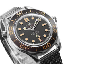 Close-up of the Seamaster Diver 300 Titanium ‘No Time to Die’ watch (42mm) with black dial, brown markers, and mesh bracelet.