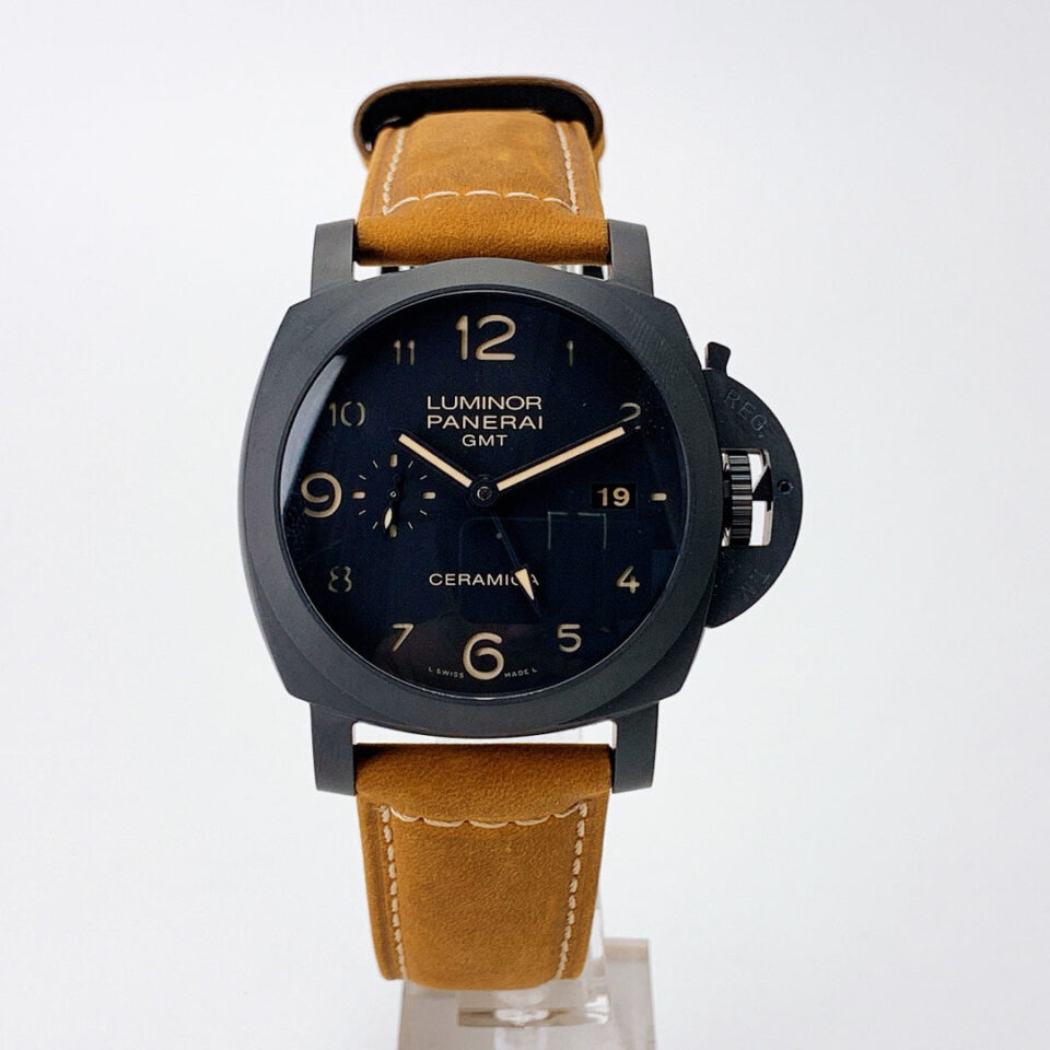 Luminor 1950 3 Days GMT Automatic Ceramica watch with a black dial and brown leather strap, displayed on a stand.