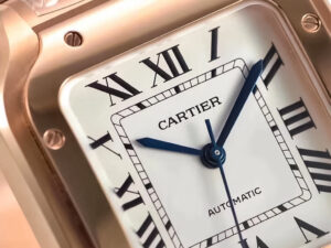 Close-up of Santos Medium Rose Gold watch with white dial, blue steel hands, black Roman numerals, "Automatic" text on face.