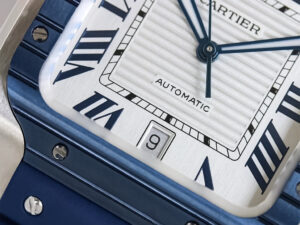 Close-up of Santos Large Stainless Steel watch with white dial, blue bezel, bold Roman numerals, and a rubber strap (40mm).