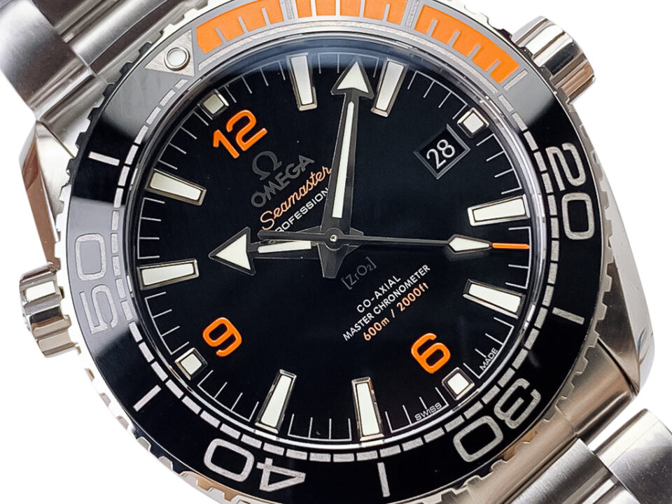 Close-up view of the Seamaster Planet Ocean 600 with Black Dial, featuring orange accents and a stainless steel bracelet.