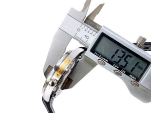 Close-up of the Seamaster Diver 300 'James Bond' (42mm)  being measured with calipers showing 13.51mm thickness.