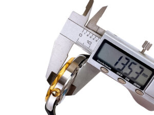Close-up of caliper measuring the thickness (13.53mm) of the Seamaster Diver 300 Stainless Steel with Black Dial Gold Bezel.