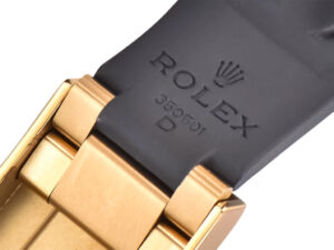 Close-up of the Cosmograph Daytona Yellow Gold Oysterflex bracelet clasp, featuring engraving and durable black rubber strap.