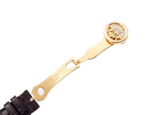 Close-up of the 18k yellow gold buckle with Patek Philippe logo, attached to a black leather strap for the Calatrava watch.