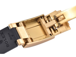 Close-up of the gold clasp and black Oysterflex strap of the Cosmograph Daytona Yellow Gold watch.