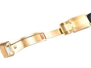 Close-up view of the Cosmograph Daytona Yellow Gold Oysterflex clasp, showcasing the gold finish and black strap detail.