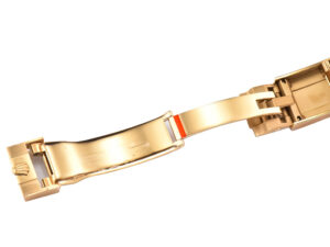 Gold clasp of the Cosmograph Daytona Yellow Gold Oysterflex with a partially visible red accent band, shown up close.