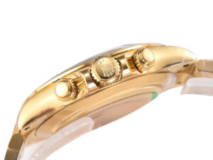 Side view of the Cosmograph Daytona Yellow Gold showcasing the gold crown and pushers against a polished finish.