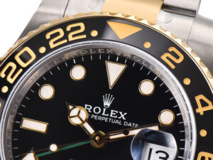 Close-up of GMT-Master II Two-Tone Rolesor watch face, featuring black dial, gold accents, date display on Oyster bracelet.